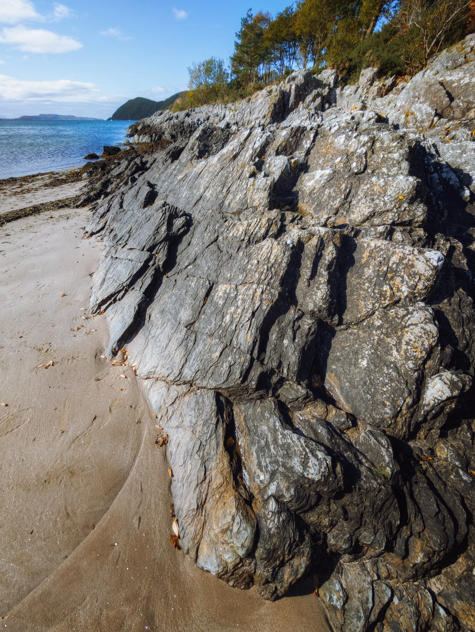 Along the northern part of the bay, these beautiful crags and formations are revealed. They are largely metamorphosed sedimentary rocks, primarily of Dalradian origin dating back to the late Precambrian era, formed over 541 million years ago.