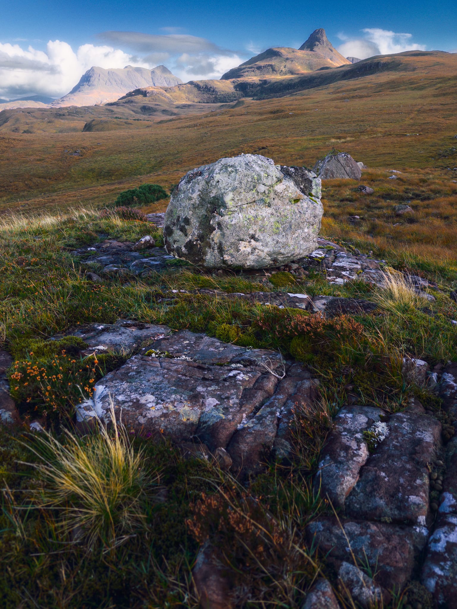I knew on the moorland of Druim Bad a’ Ghaill that there were various sandstone outcrops with glacial erratics perched on them. I just didn’t know where specifically. Thankfully, from near the power generator we parked near, I sighted a lone boulder perched on a platform further down the road. After some squelching and slipping, I found my composition that also happily included Stac Pollaidh and Cùl Mòr.