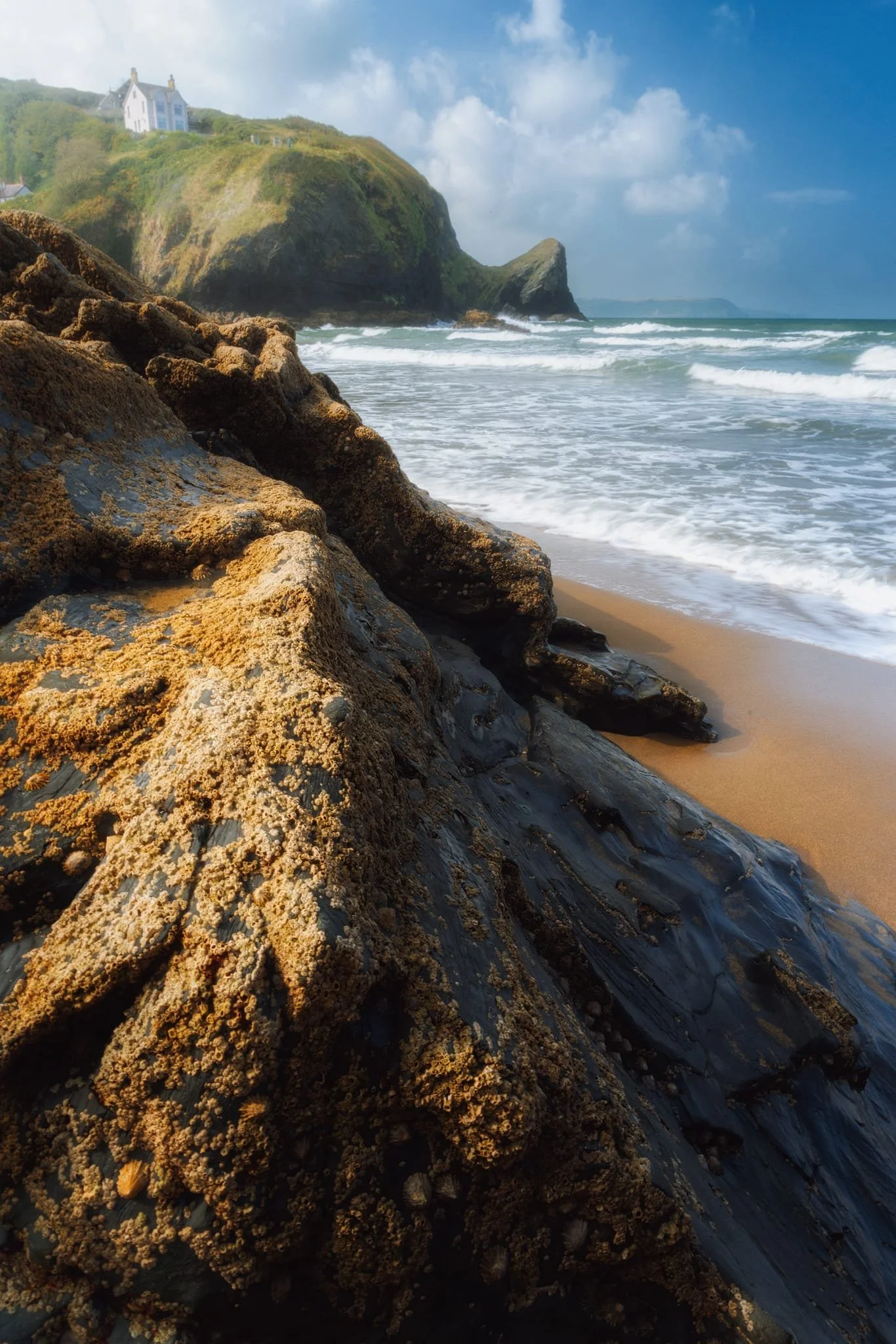 Looking to Llangrannog’s southern cliffs, and the pointy crag of Pen-rhip , I wait for the sun to strike this beach boulder and use the lighting as a leading line into the composition.