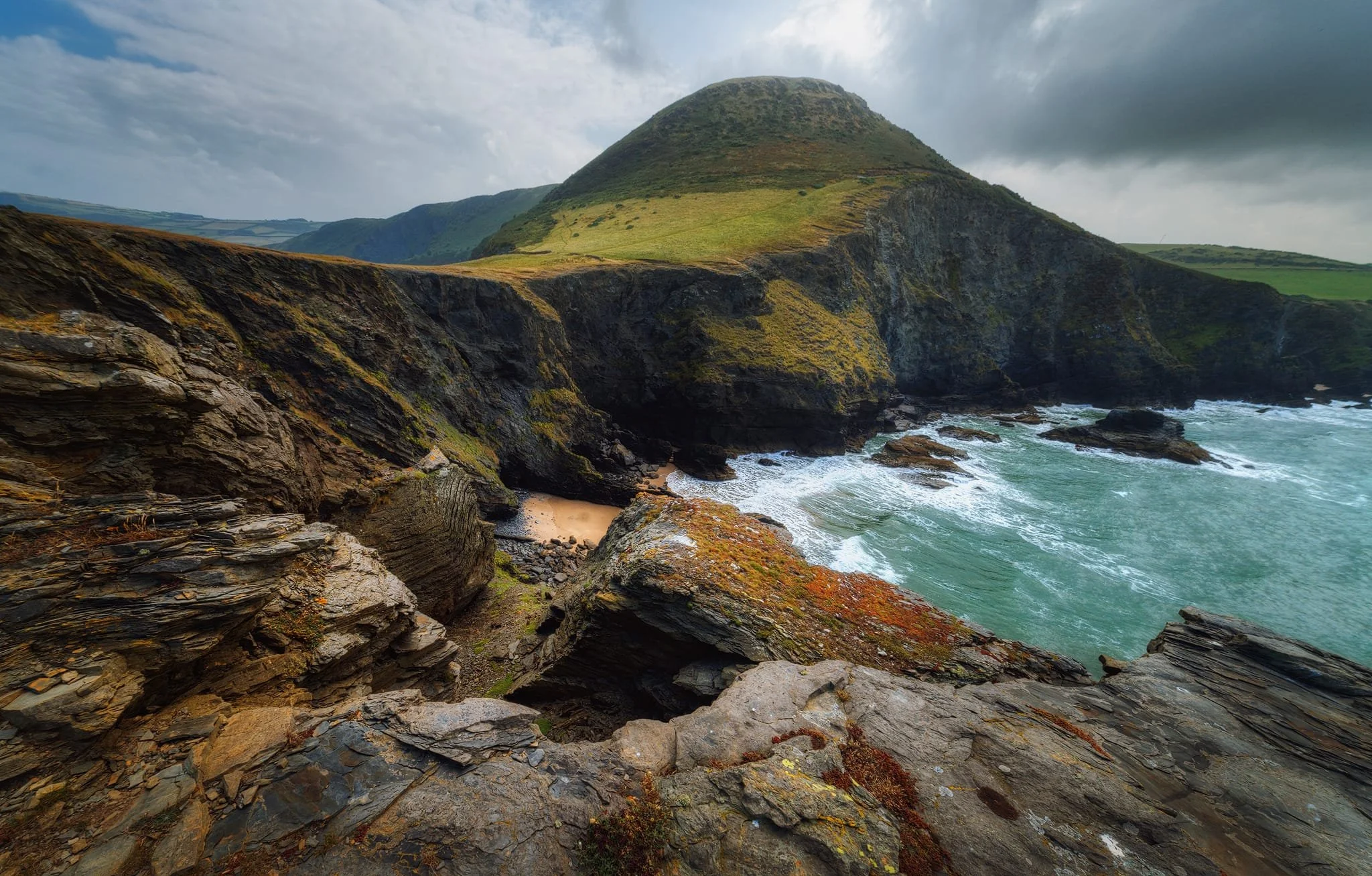 Even with my 14mm ultra-wide angle lens attached, the scenes were so vast that I had to do some stitching for wide views. This composition was made of four 14mm images, stitched together to get all the incredible cliff face geology as well as the sea, hill, and dramatic sky.