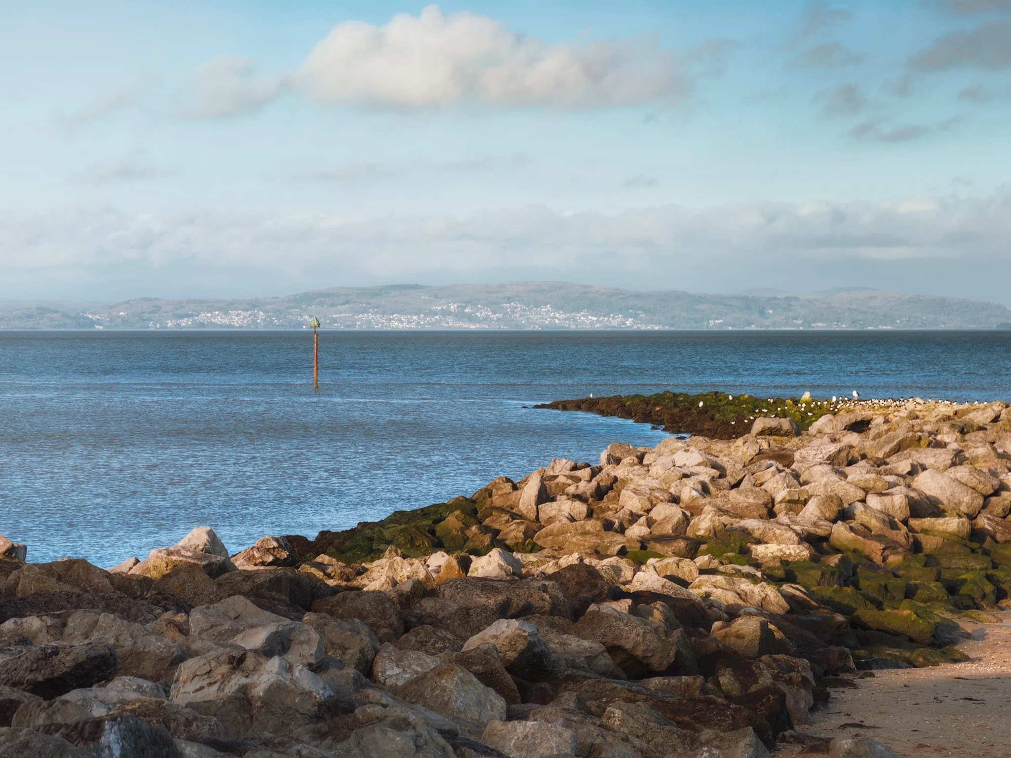 The clarity of light allowed for a zoomed in composition of one of Morecambe’s bouldered breakwaters, using its curve as a leading line towards the distant Grange-over-Sands, all the way the other side of the bay.