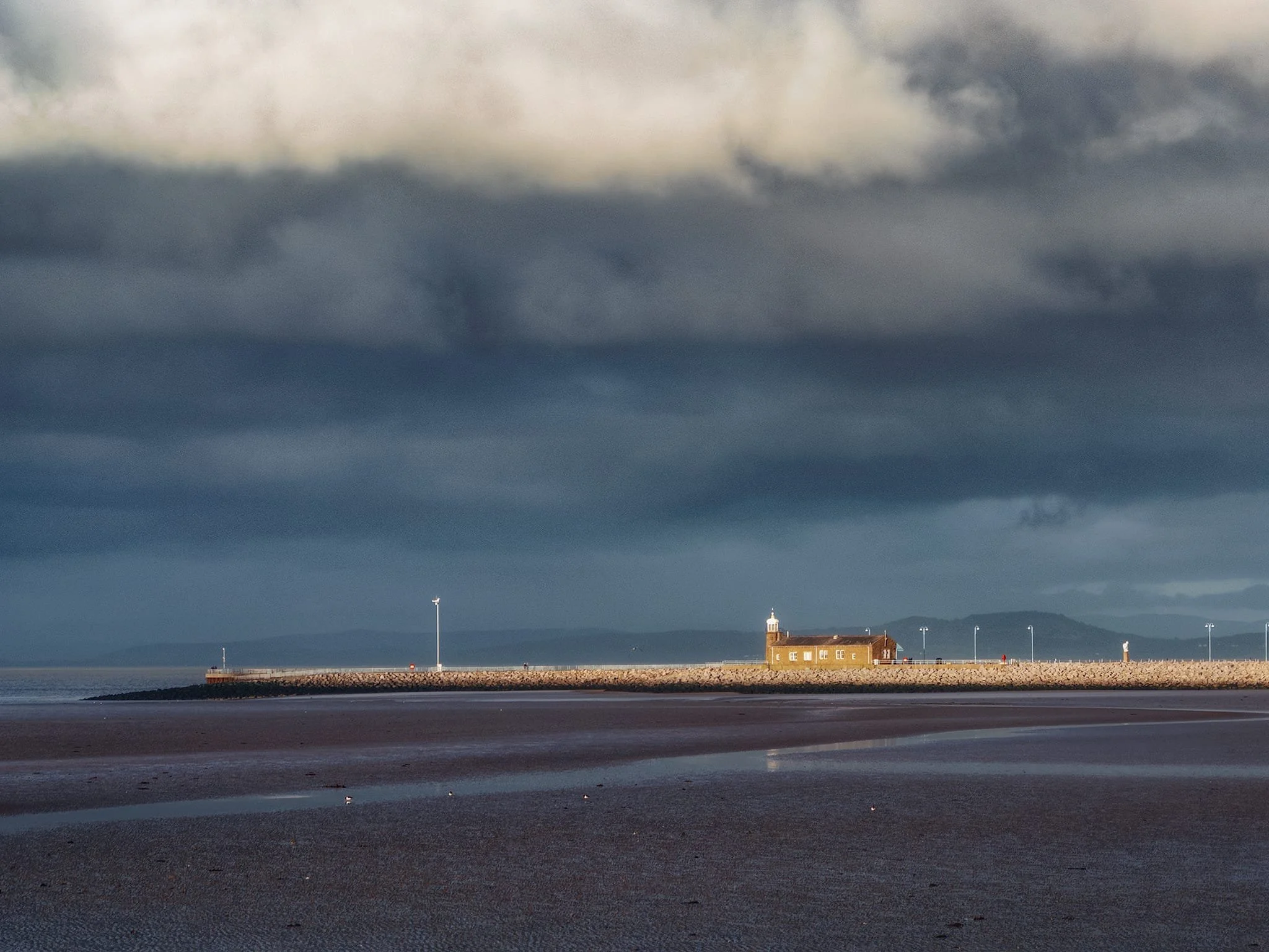 Further out along the stone jetty is the abandoned Stone Jetty Cafe, saturated in amber hues as stormy clouds build in the sky.