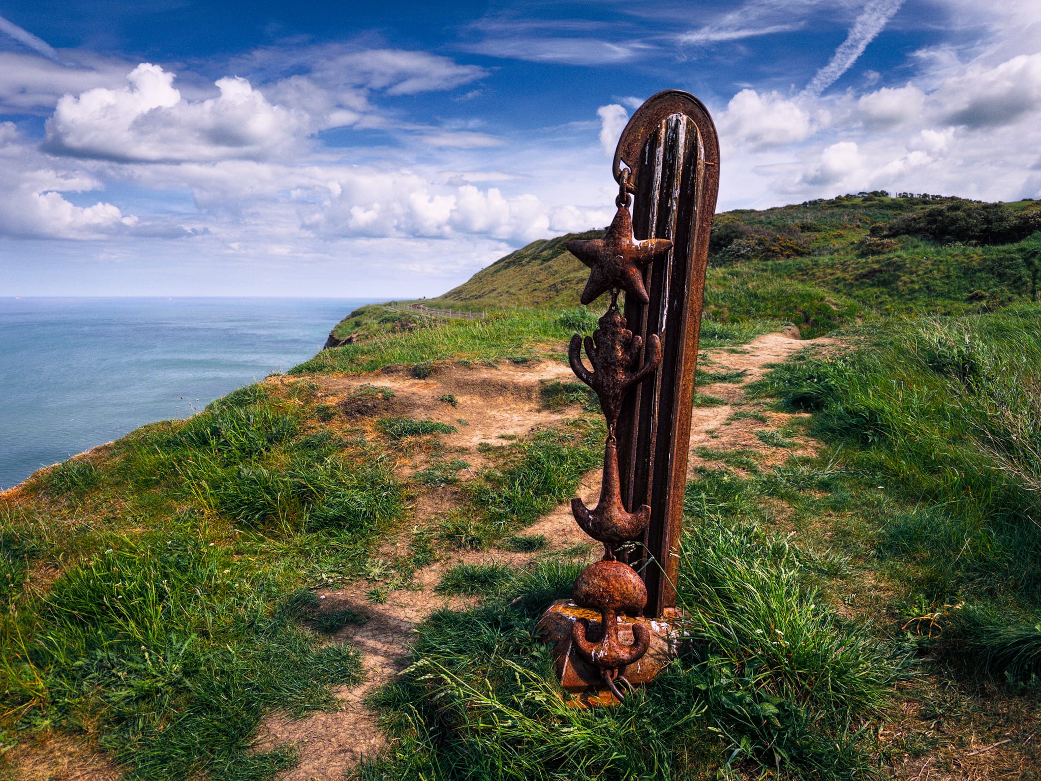 Along the way, we came across this interesting iron-wrought sculpture. This piece is called “Pillar”. Created by Richard Farrington in 1990 as part of a series of three clifftop steel artworks near Huntcliff on the Cleveland Way. The chain of four vertical metal charms on the post is designed to represent: A star at the top, the tip of a growing plant, the shape air makes when hitting a surface, and a jellyfish reflecting in the water at the bottom. Neat.