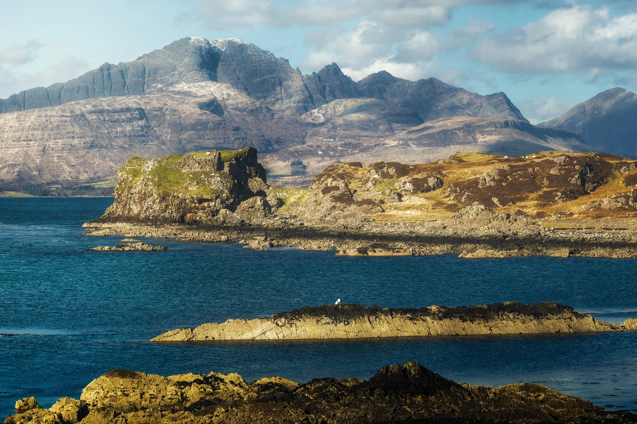 Moving on from Tarskavaig, we continue up the northern shore of Sleat to Tokavaig. At Tokavaig Bay, one can find the ruins of Dùn Scaich castle, formerly owned by Clan MacDonald of Sleat, a branch of the Clan Donald or MacDonald. With my long zoom lens, I can really compress the distant views, capturing the ruins of the castle as well as the mighty Blàbheinn mountain in the distance.