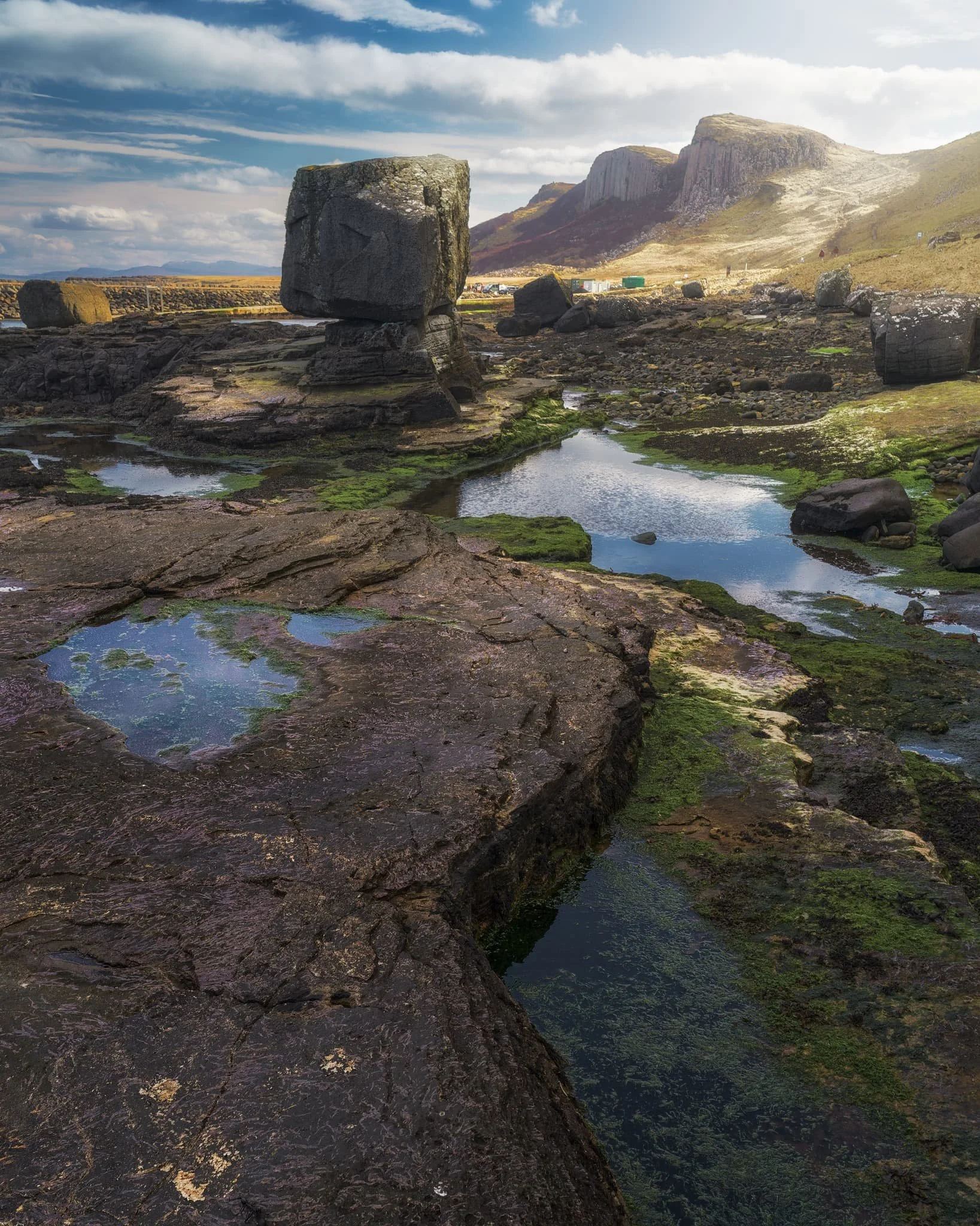 Picking my way around slippery slabs, moss, and seaweed, I lined up this composition of the raised boulder, with the basalt cliffs in the distance.