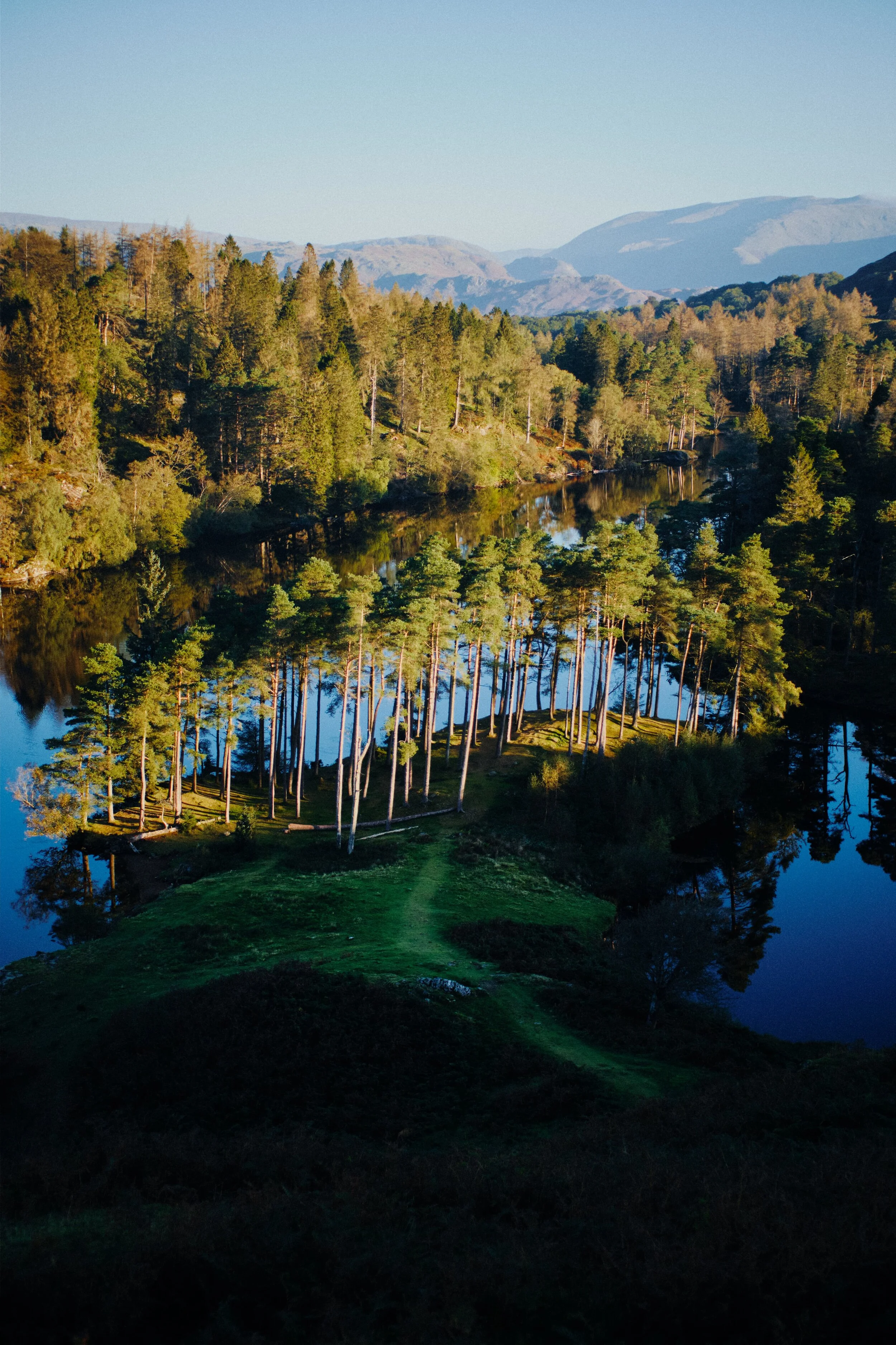 Looking down to Tarn Hows from the crags above it. Beyond are the Grasmere Fells.