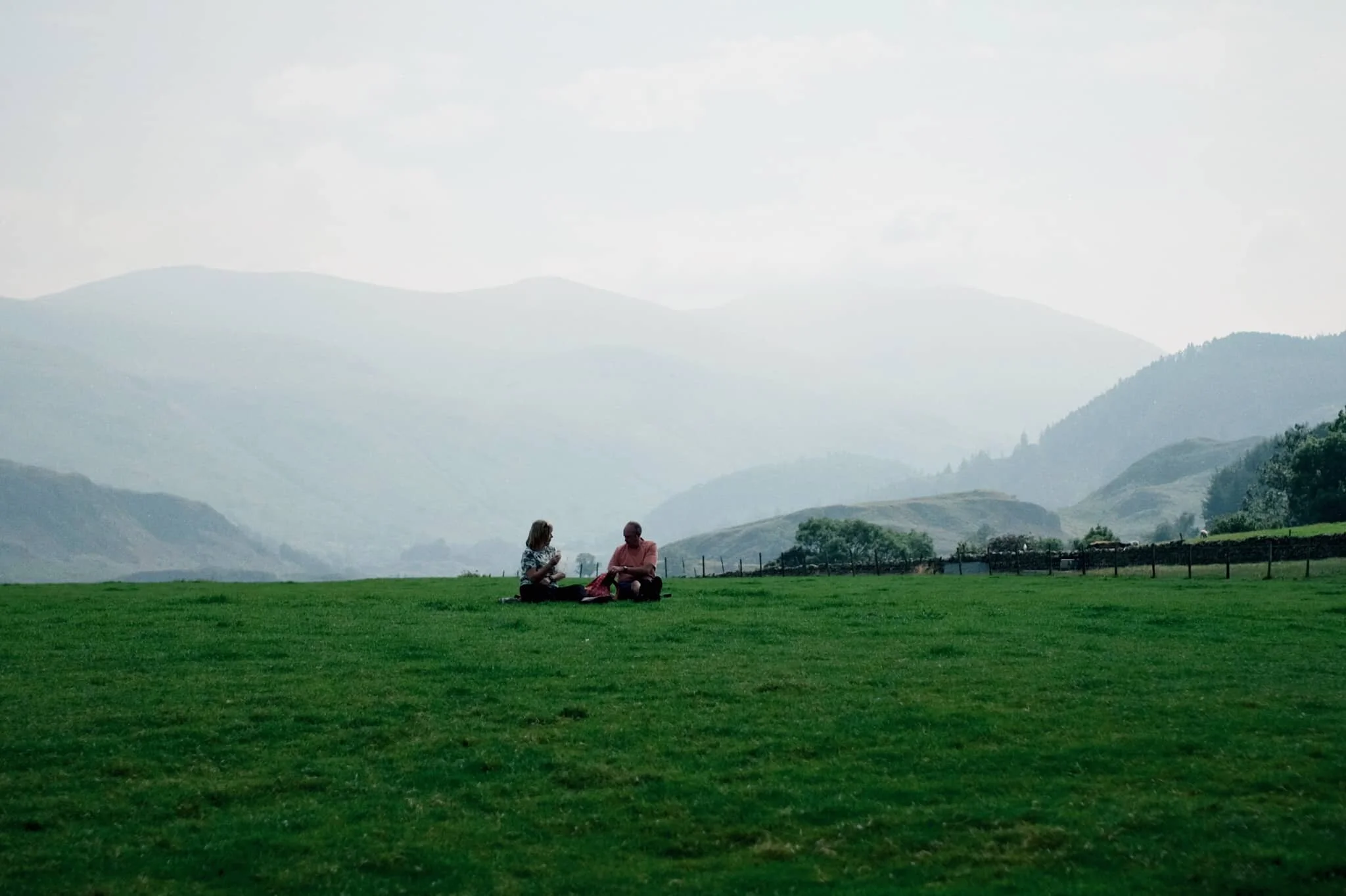 Not far along the trail and already the views really open up. A couple enjoy a picnic in the sun with the backdrop of the Helvellyn fells behind them.