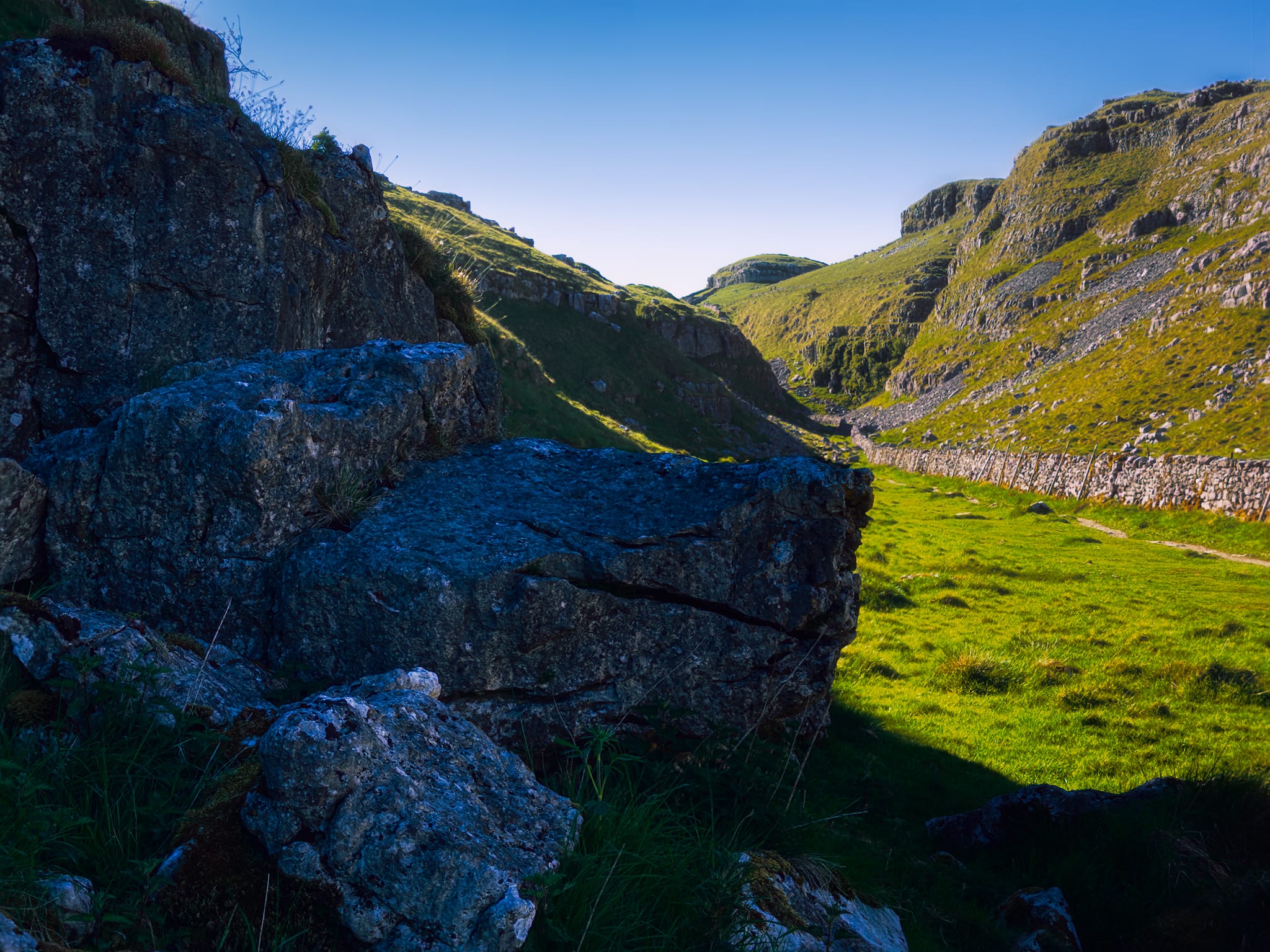 Another cluster of limestone boulders deep in the shade provide another contrasting composition with the valley’s high crags towering above.