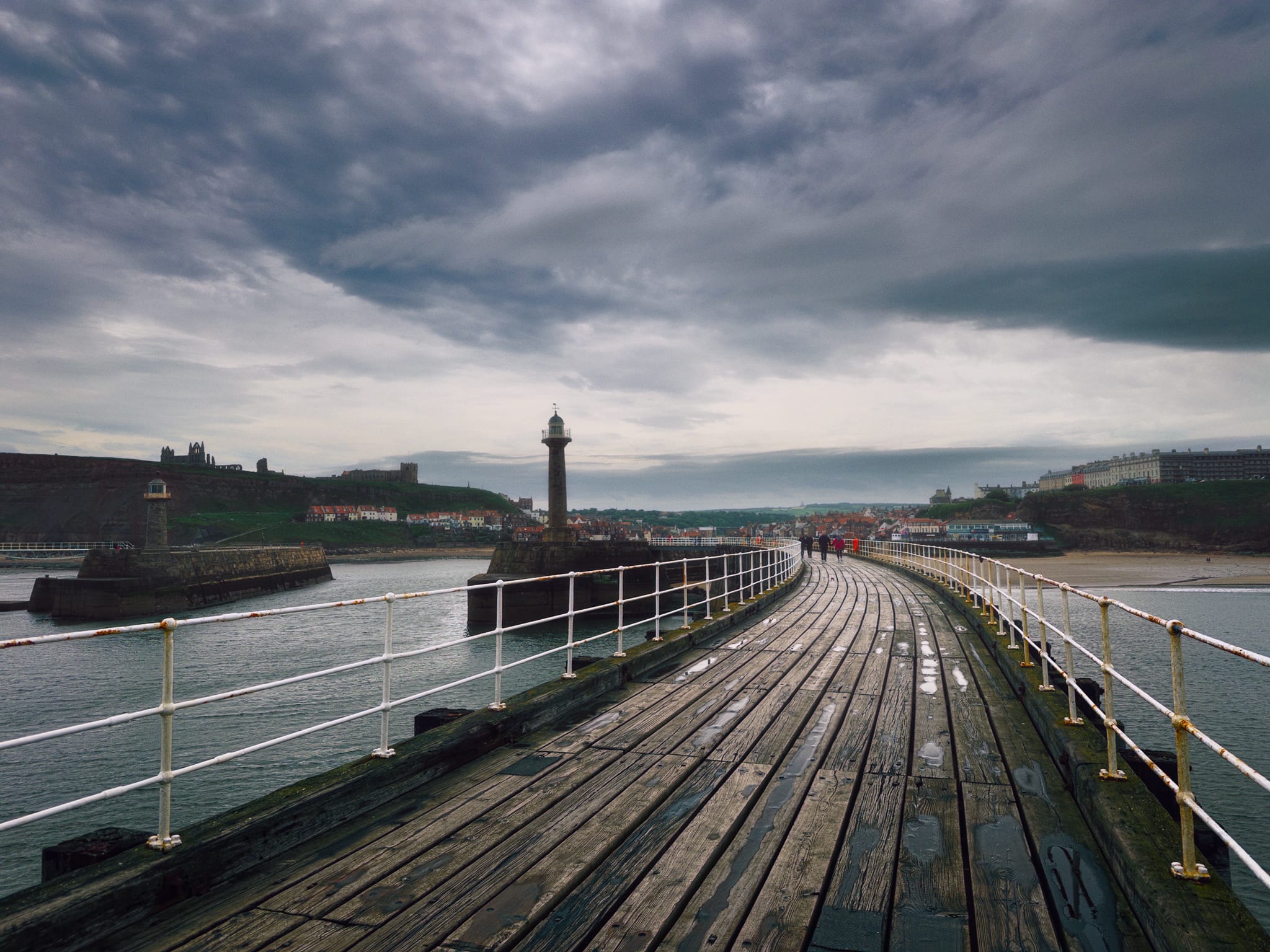Looking back from the end of the West Pier, clouds racing above. On the cliffs to the far left is Whitby Abbey with St Mary’s Church a little further in. To the left in the sea is Whitby East Pier Lighthouse, with the West Pier Lighthouse more central. To the right on the cliff is the newer part of Whitby, with Victorian buildings constructed to accommodate Whitby’s then growing status as a tourist destination.