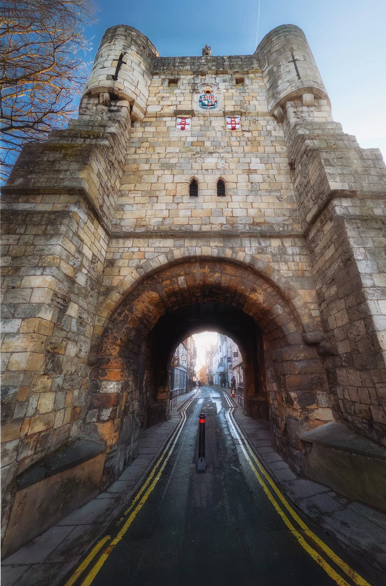This gatehouse is Bootham Bar, one of four main “bars” that punctuate the ancient city walls of York. Though largely rebuilt in the 14th and 19th centuries, Bootham Bar retains 11th-century stonework, the oldest surviving. It stands near the site of the Roman northwest gate, taking its name from the 12th-century